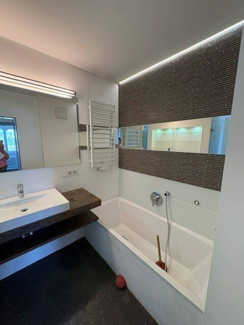 Badezimmer mit Badewanne, modernem Waschbecken und beheiztem Handtuchhalter.