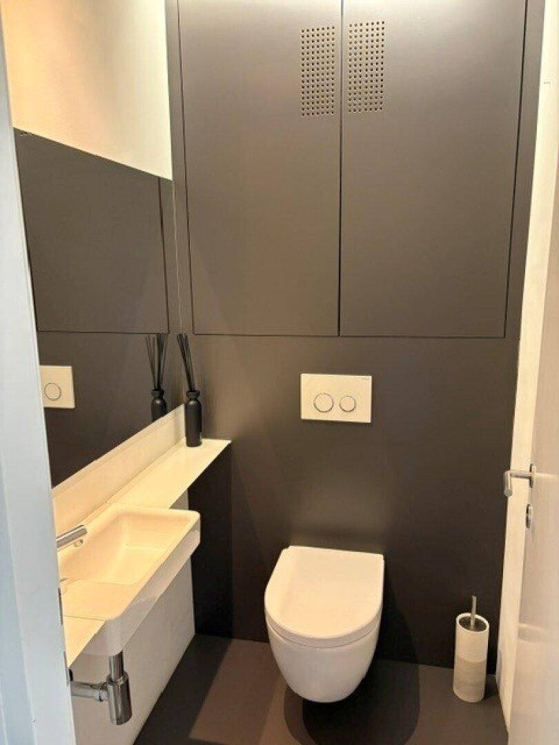Modernes Gäste-WC mit Wand-WC, kleinem Waschbecken und Spiegelschrank.