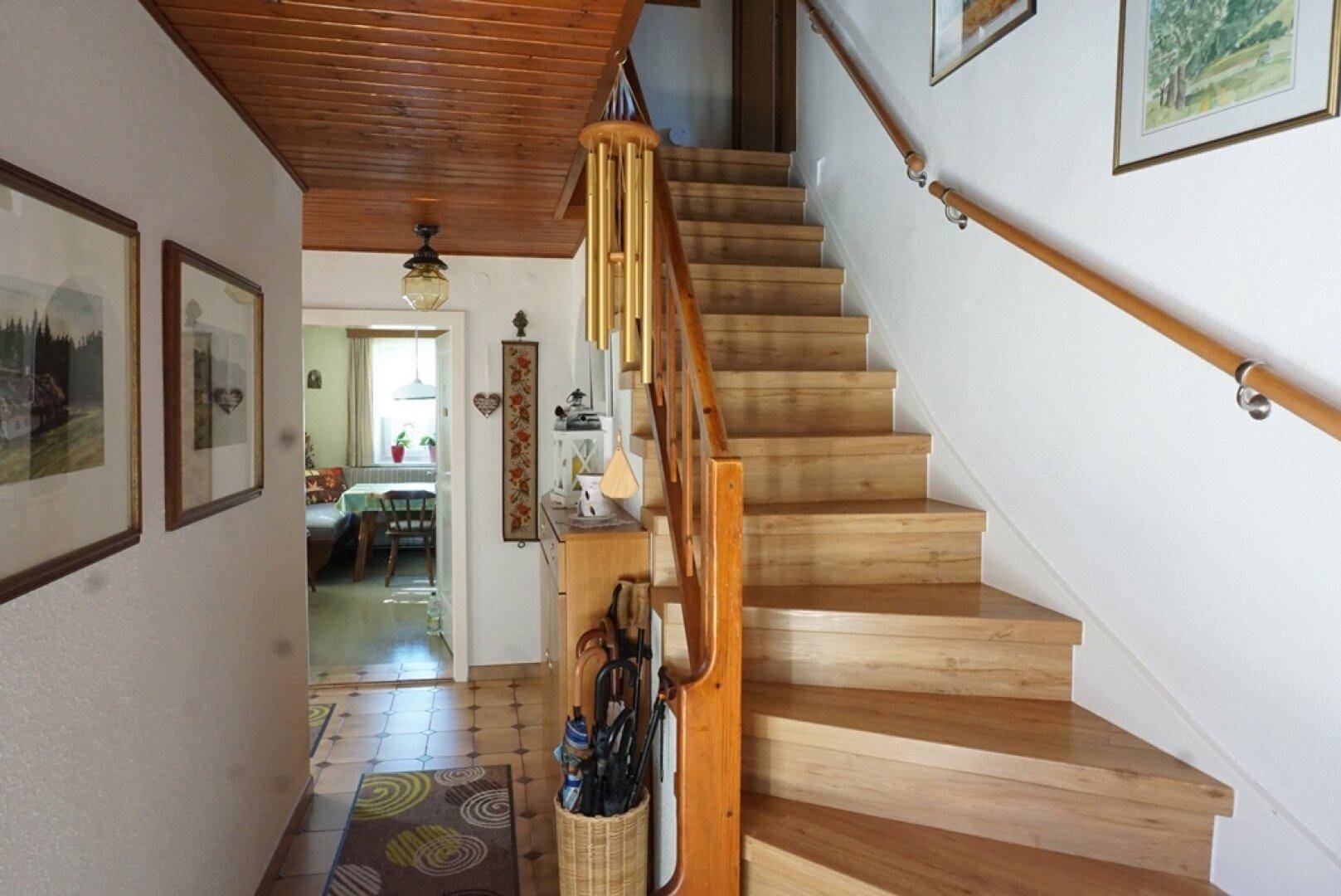 Heller Flur mit Holztreppe und Holzdecke, der zu weiteren Räumen führt.