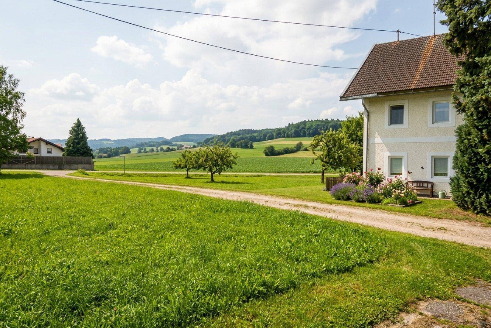Ländliches Anwesen mit einem Haus, großem Rasen und weitem Blick über grüne Felder und sanfte Hügel.