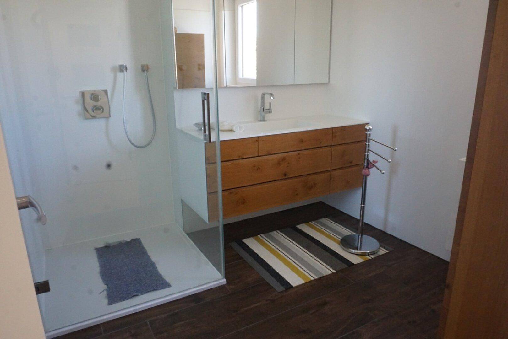 Modernes Badezimmer mit begehbarer Dusche, Holzwaschtisch und Spiegelschrank.