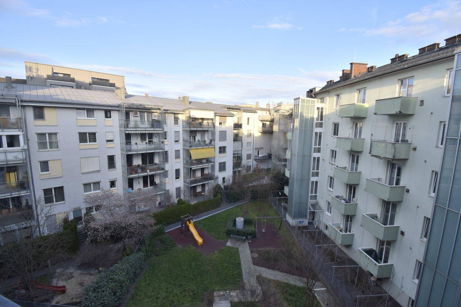 Blick auf den begrünten Innenhof mit Spielplatz, umgeben von Wohngebäuden.