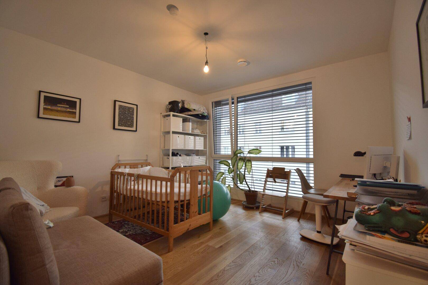 Vielseitiges Zimmer mit Kinderbett, Schreibtisch und Sofa, ideal als Kinder- oder Arbeitszimmer.