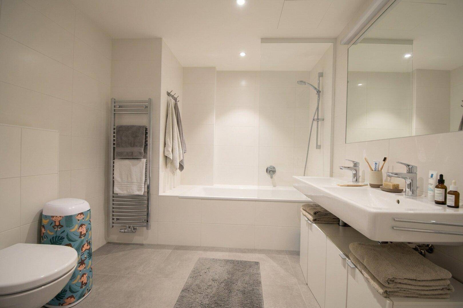Helles Badezimmer mit Badewanne, Dusche, WC, Waschbecken und beheiztem Handtuchhalter.