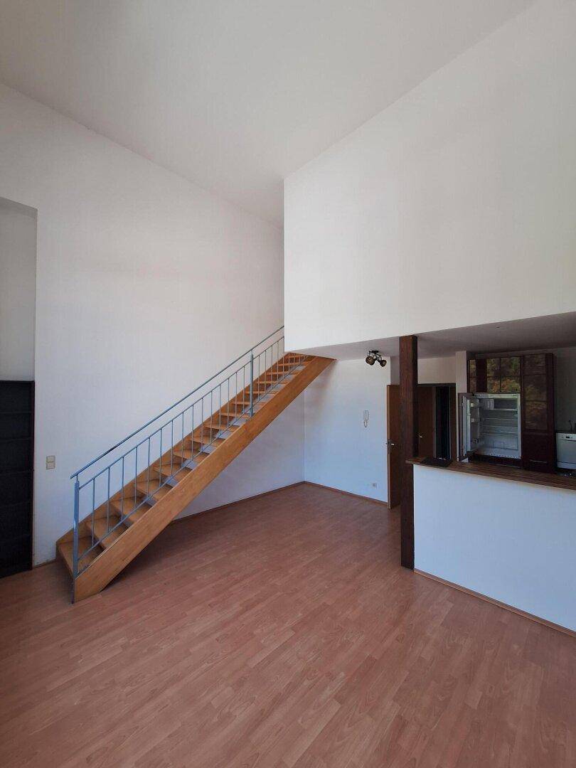 Geräumiger Wohnbereich mit offener Treppe und angrenzendem Küchenbereich, ideal für offenes Wohnen.