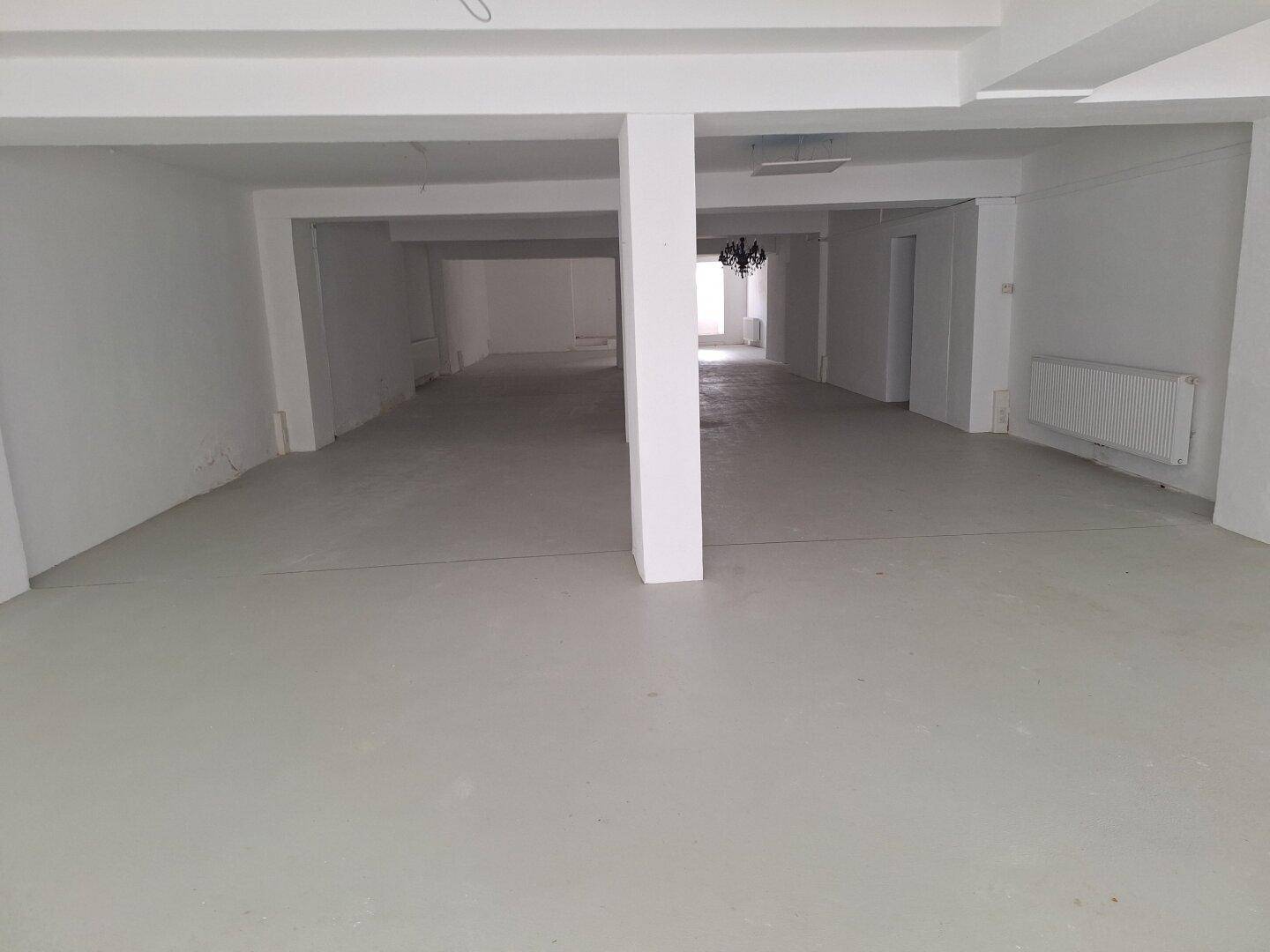 Geräumiger, leerer Ladenbereich mit hohen Decken und tragenden Säulen, bereit für den Ausbau.