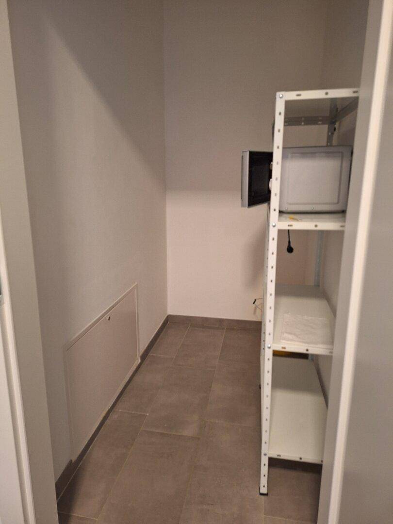 Praktischer Abstellraum mit Regalen und gefliestem Boden für zusätzlichen Stauraum.