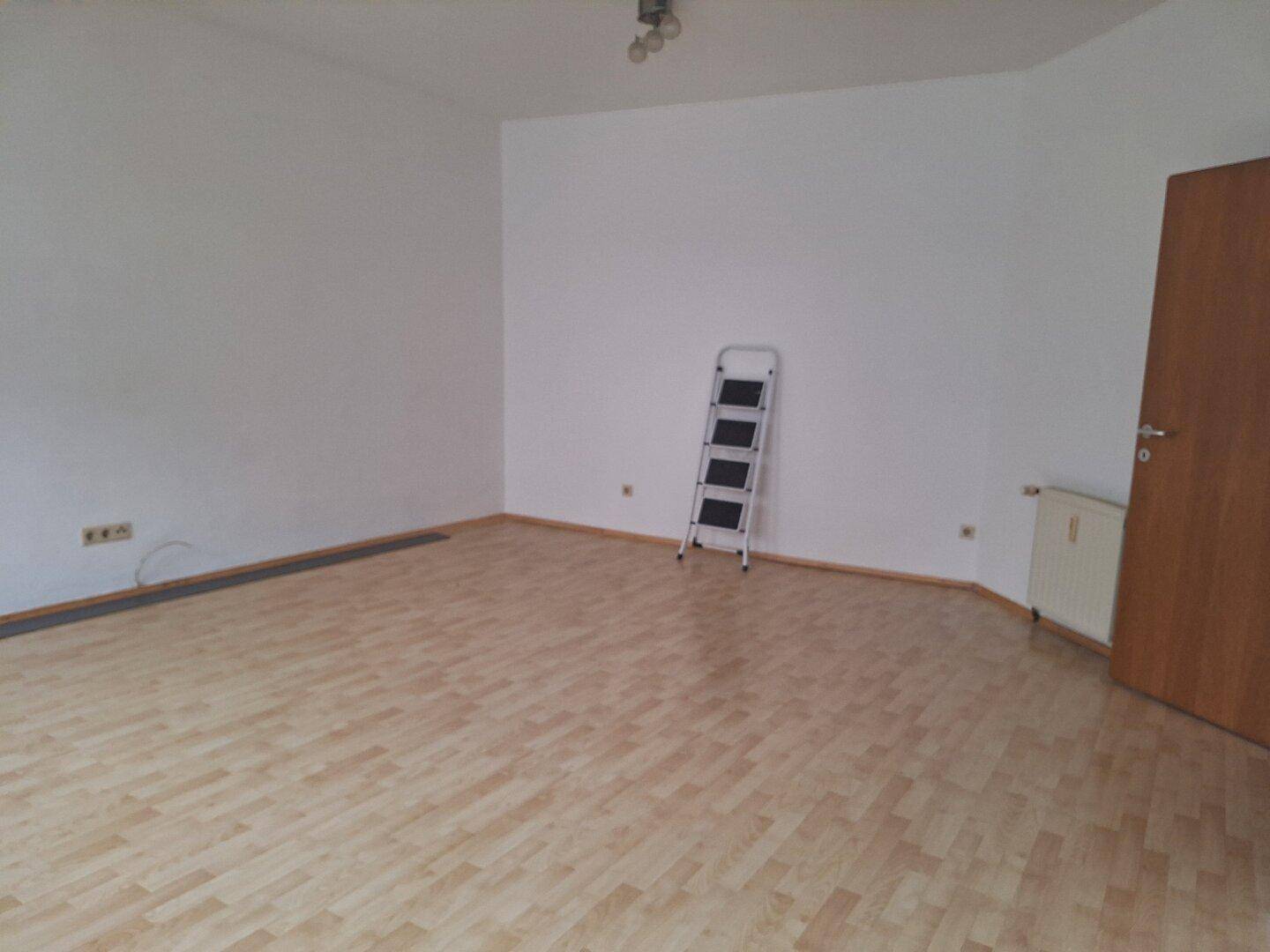 Heller, leerer Raum mit Laminatboden und weiß gestrichenen Wänden, bereit zur Einrichtung.
