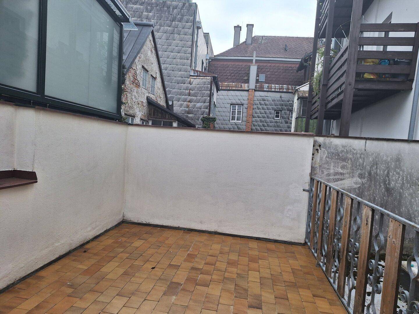 Gemütliche Terrasse mit Terrakottafliesen und Blick auf die umliegenden historischen Gebäude.