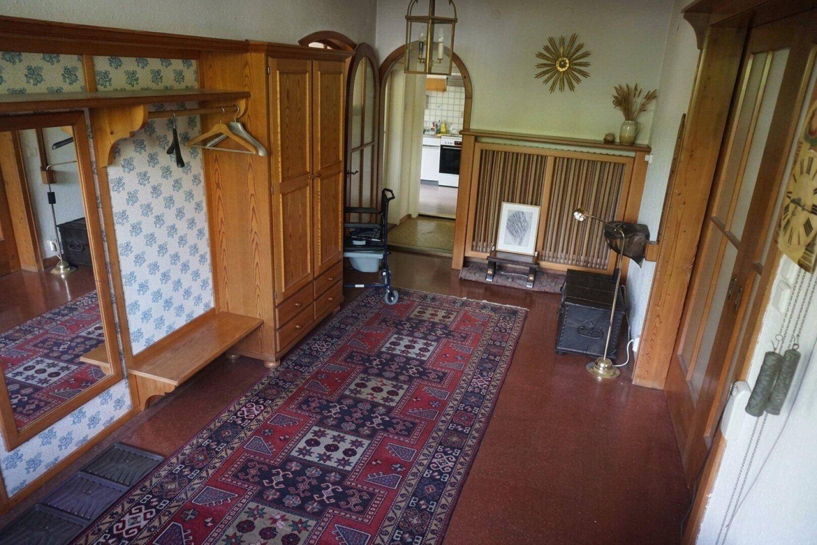 Einladender Eingangsbereich mit Garderobe, Holzschrank und traditionellem Teppich.