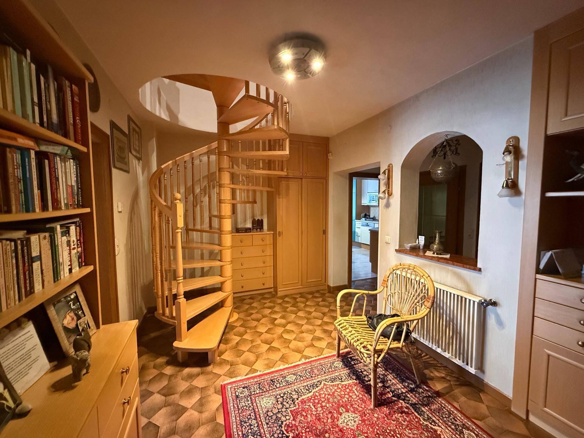 Eingangsbereich mit Holzwendeltreppe, gemustertem Fliesenboden und Einbauschränken.
