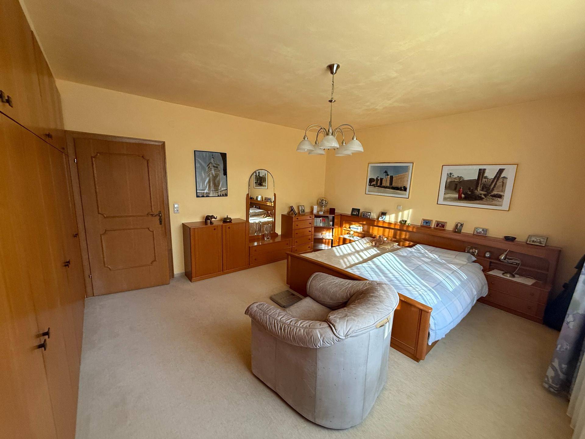 Geräumiges Schlafzimmer mit Teppichboden, Holzmöbeln und viel Stauraum.