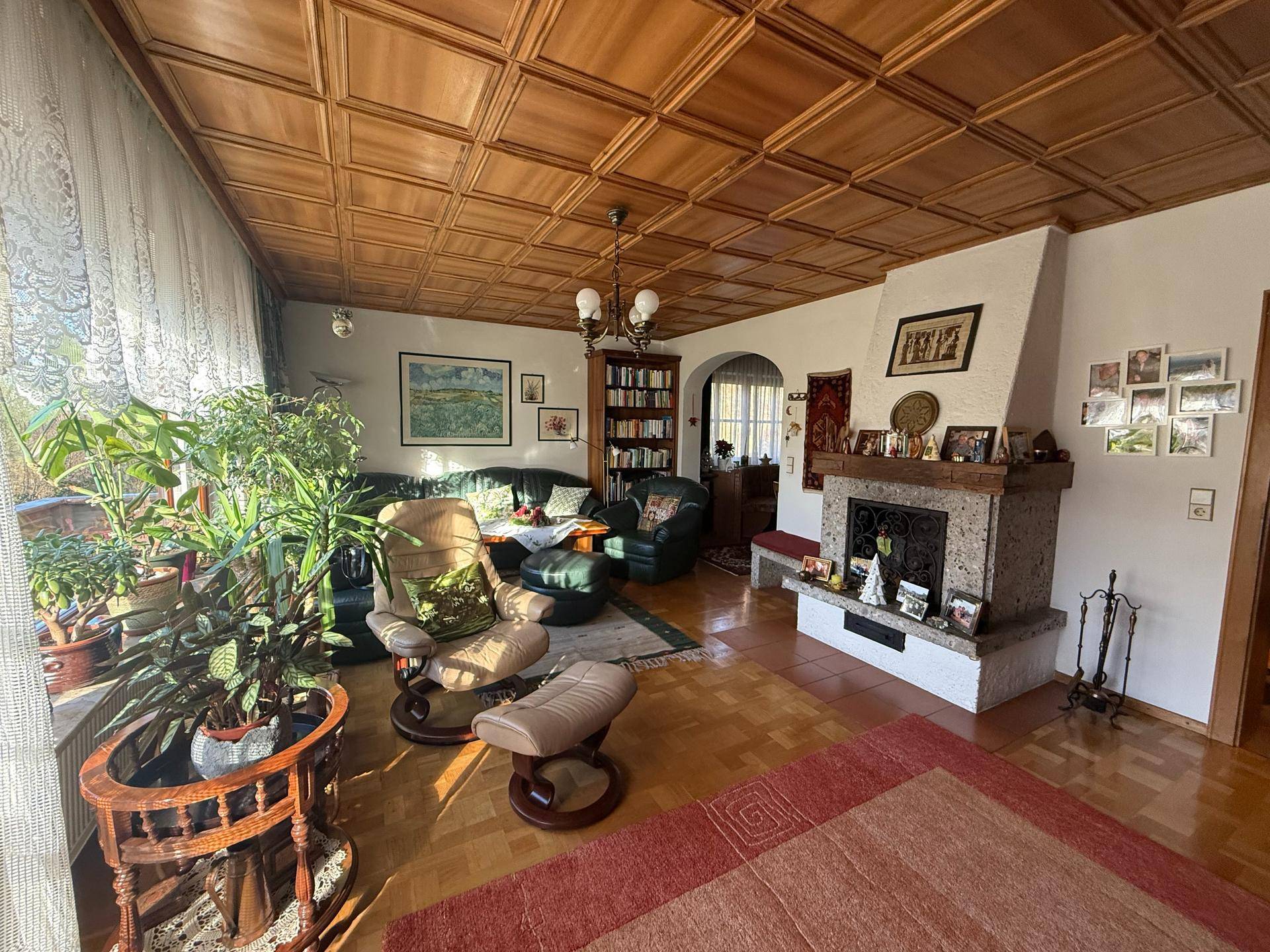 Gemütliches Wohnzimmer mit Holzkassettendecke, Kamin und traditioneller Einrichtung.