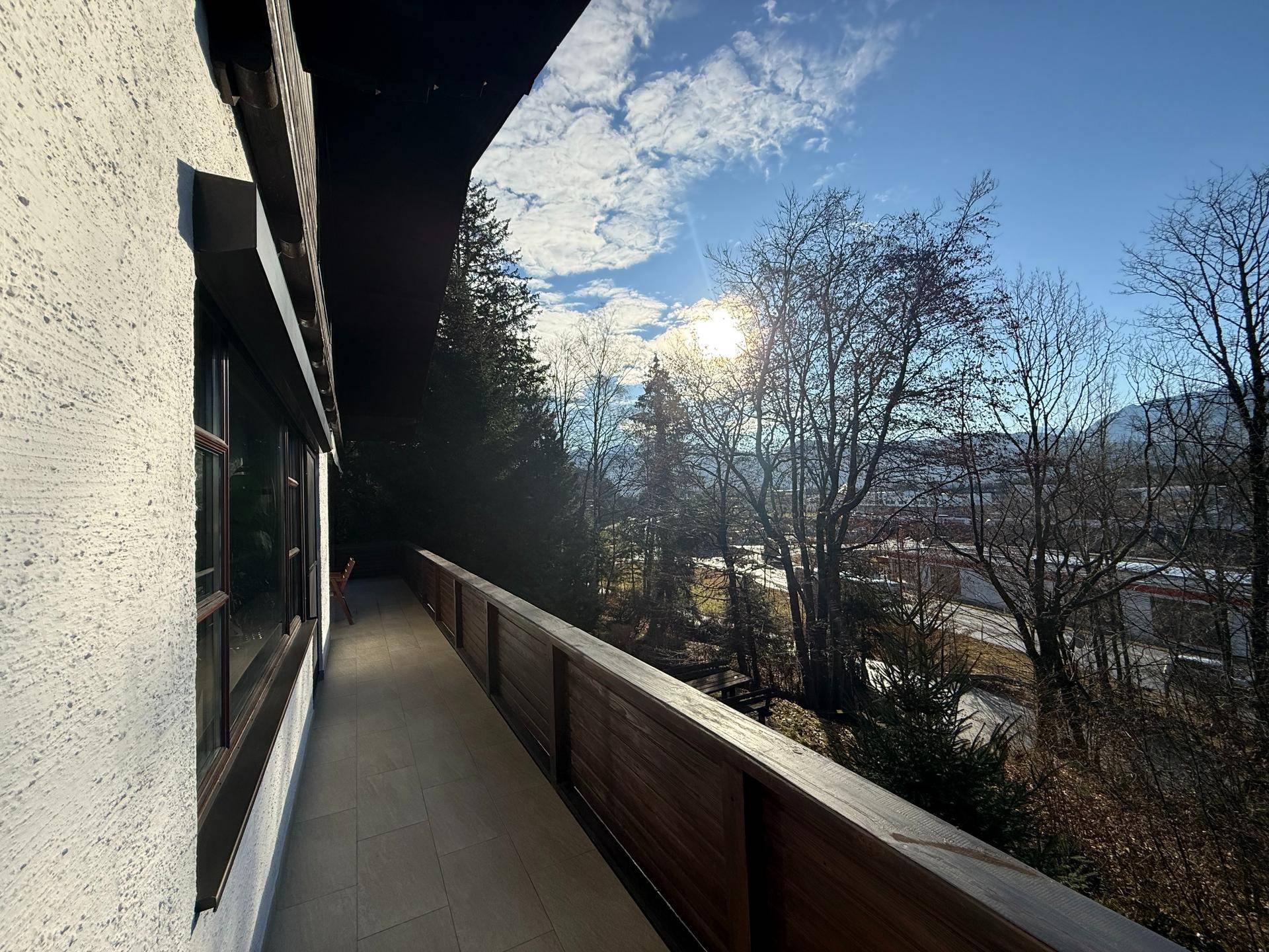 Sonniger Balkon mit Holzbalkonbrüstung und weitem Blick auf die Berge und das Tal.
