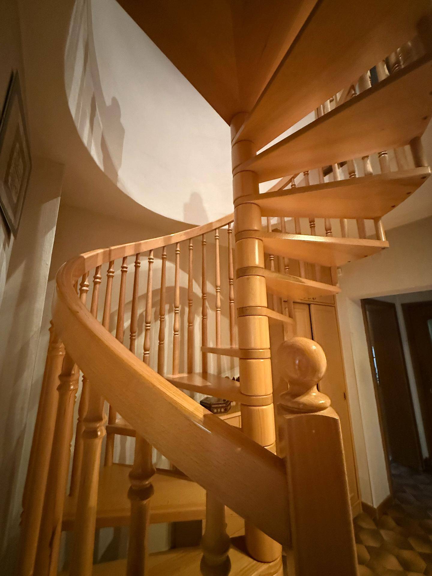 Detailansicht der eleganten Holzwendeltreppe mit gedrechselten Geländerstäben.