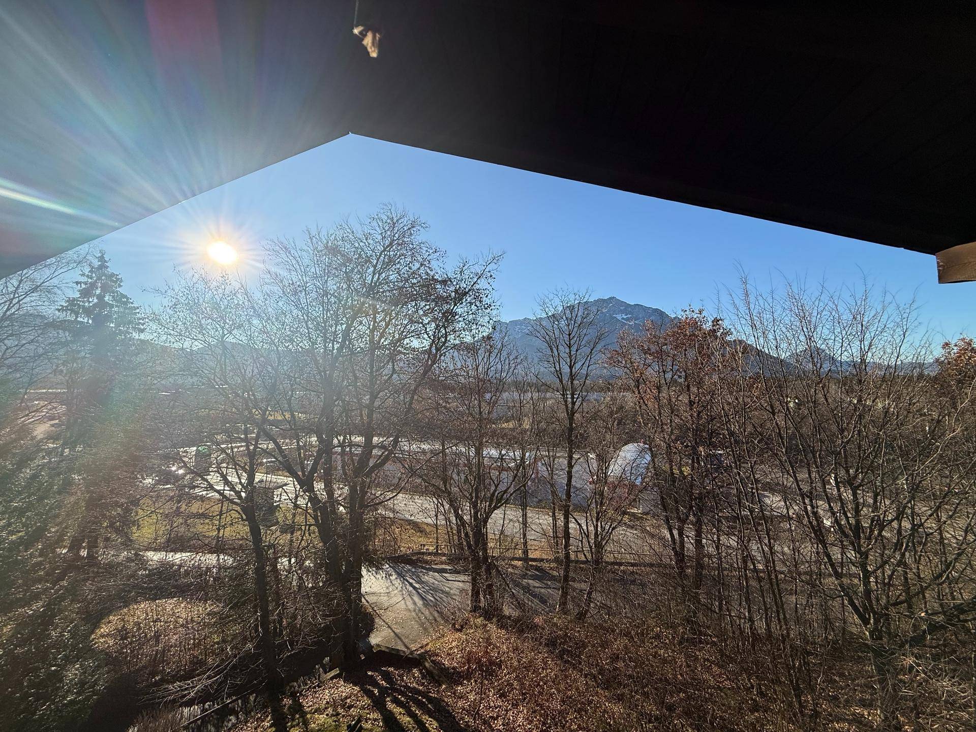 Weitläufiger Blick auf die umliegende Landschaft mit Bergen und Bäumen unter blauem Himmel.