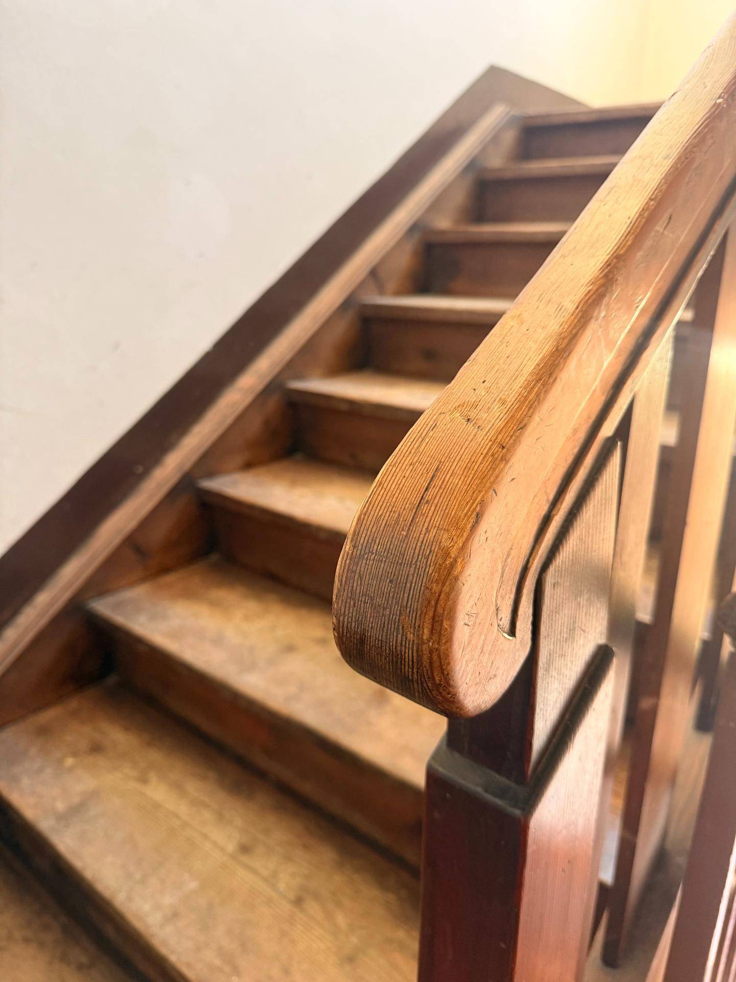 Eine alte Holztreppe mit geschnitztem Geländer führt in die obere Etage.