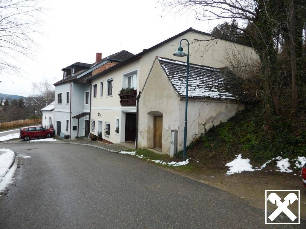 Straße mit mehreren Wohnhäusern und einem Laternenpfahl, teilweise mit Schnee bedeckt.