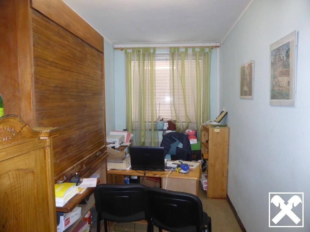 Kleines Büro oder Arbeitszimmer mit Holzmöbeln, Schreibtisch und Fenster mit grünen Vorhängen.