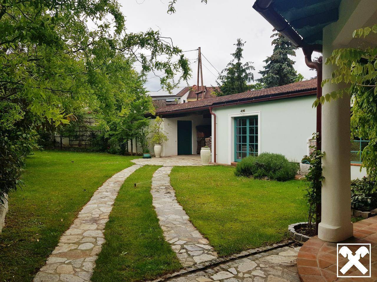 Weitläufiger Garten mit Rasenfläche, gepflastertem Weg und Blick auf das Haus.