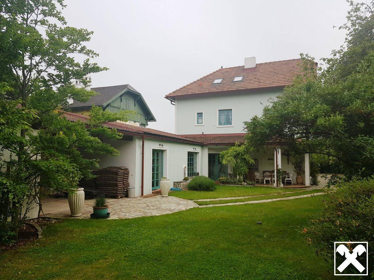 Großer Gartenbereich mit Rasen, Terrasse und der Rückseite des Wohnhauses.