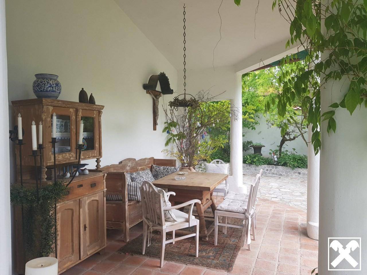 Gemütliche überdachte Terrasse mit rustikalen Holzmöbeln und traditioneller Dekoration.