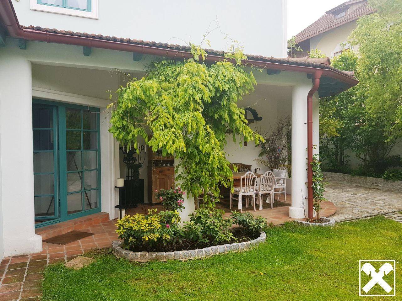 Überdachte Terrasse mit Gartenmöbeln und direktem Zugang zum grünen Gartenbereich.