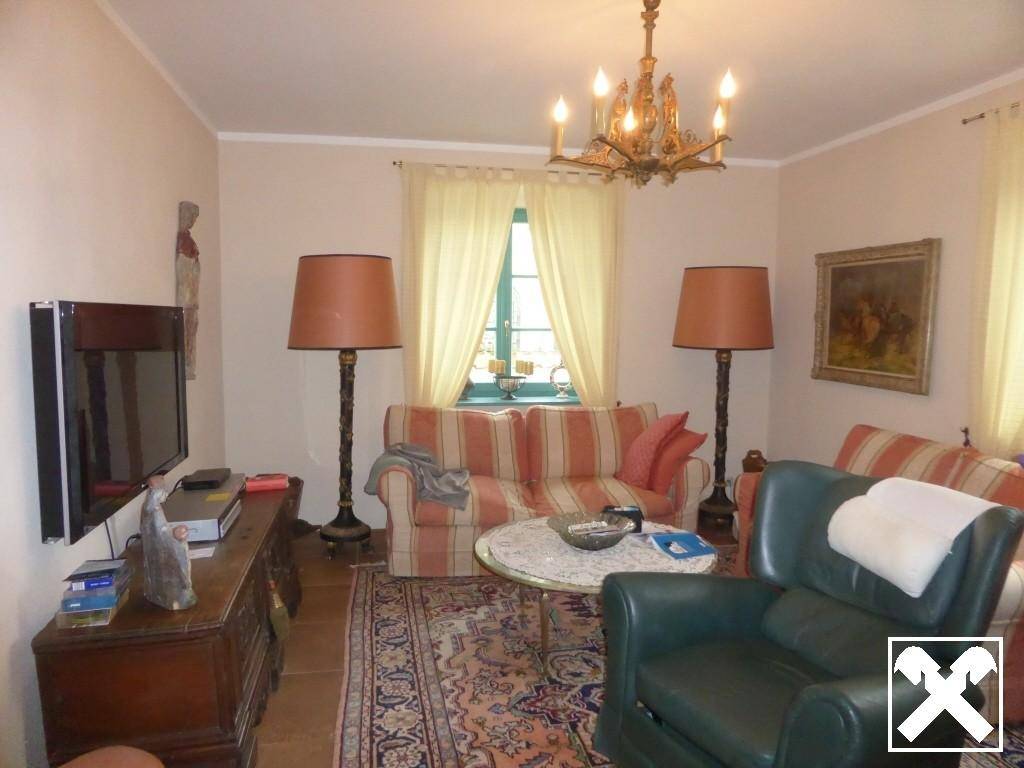 Gemütliches Wohnzimmer mit gestreiften Sofas, Teppich und traditionellem Kronleuchter.