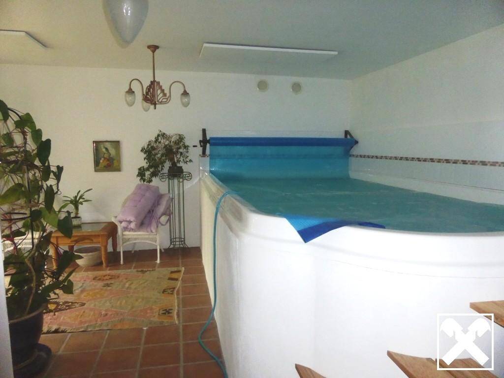 Innenpoolbereich mit Schwimmbecken, Fliesenboden und Pflanzen für eine entspannte Atmosphäre.