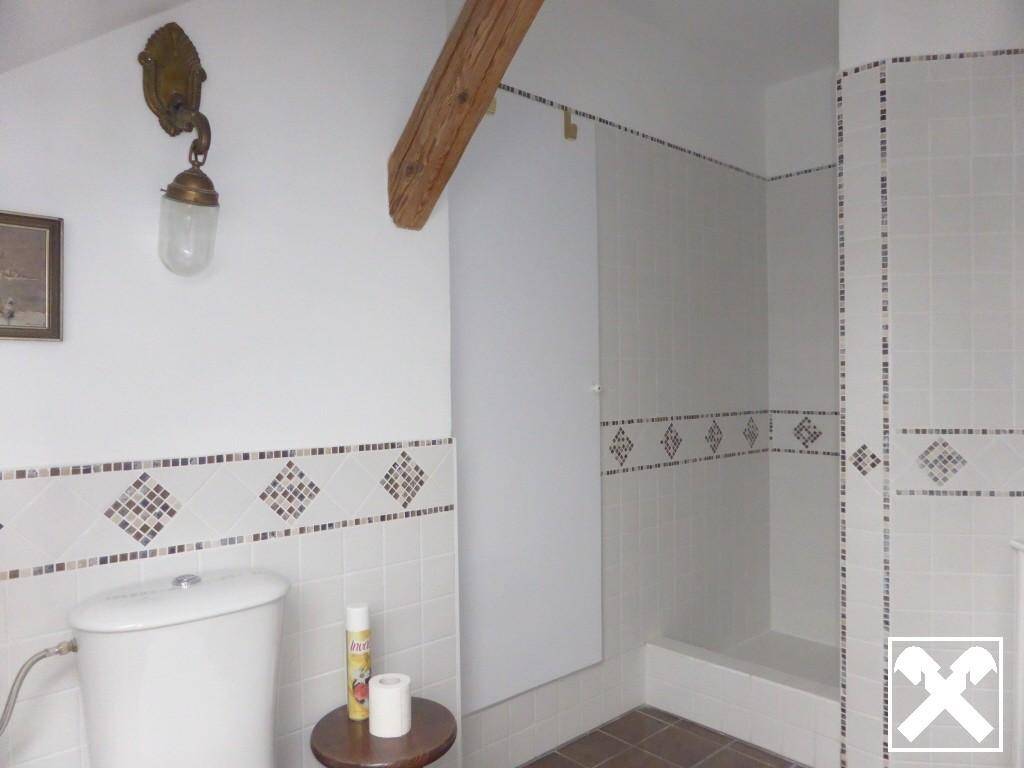 Badezimmer mit Duschbereich, WC und dekorativen Fliesen an den Wänden.
