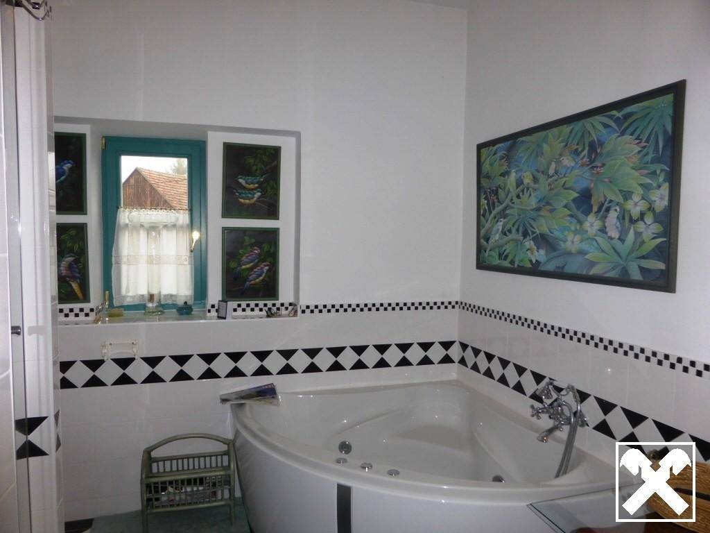 Badezimmer mit Eckbadewanne, Fliesen in Schwarz-Weiß-Muster und Fenster.