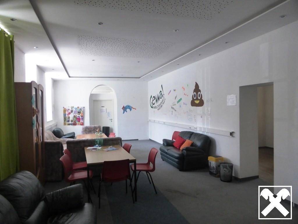 Geräumiger Gemeinschaftsraum mit Sitzgelegenheiten, Tischen und kreativen Wanddekorationen.