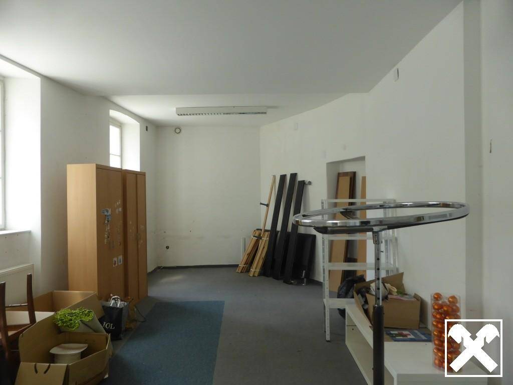 Leerer Mehrzweckraum mit Teppichboden und Fenstern, bereit für verschiedene Nutzungsmöglichkeiten.