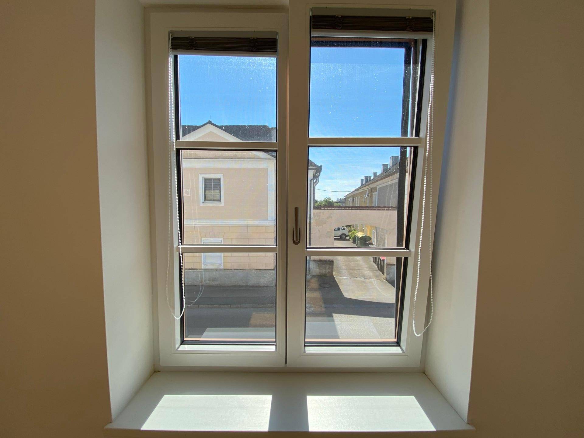 Helles Fenster mit Blick auf einen Innenhof oder eine ruhige Gasse.