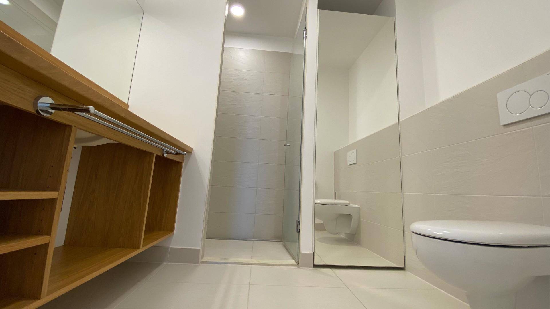 Modernes Badezimmer mit begehbarer Dusche, wandhängendem WC und hellen Fliesen.