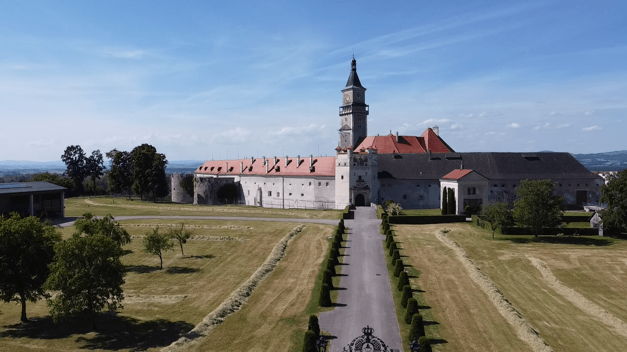 Beeindruckendes historisches Schloss mit weitläufiger Zufahrt und gepflegter Grünanlage.