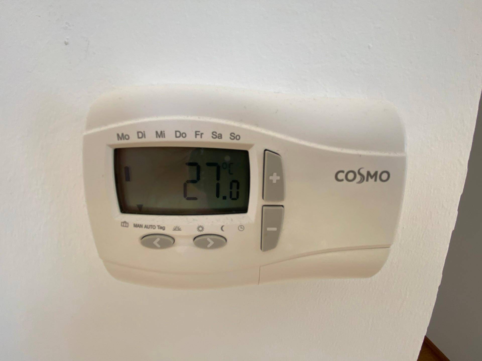 Digitaler Thermostat zur Steuerung der Raumtemperatur an einer weißen Wand.