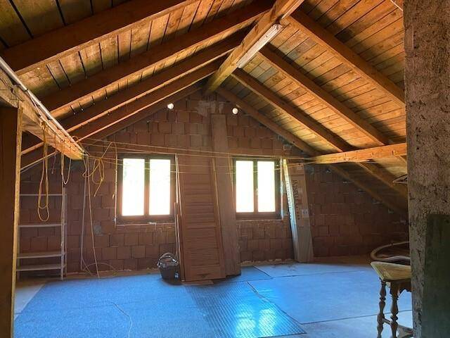 Unausgebauter Dachboden mit sichtbaren Holzbalken und zwei Fenstern, bietet Ausbaupotenzial.