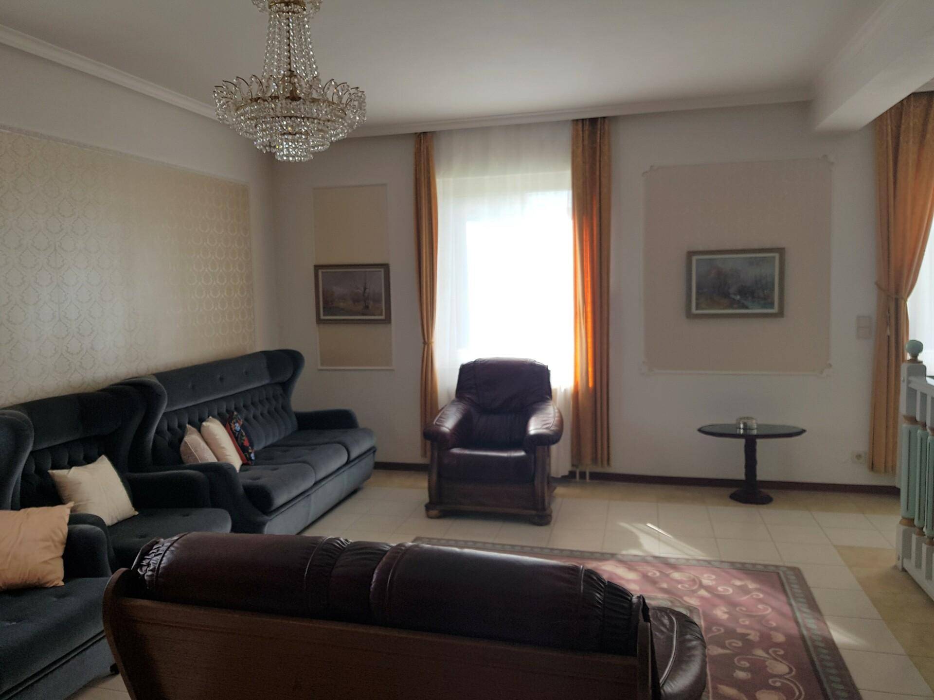 Klassisch eingerichtetes Wohnzimmer mit Ledersofa, Teppich und dekorativen Wandelementen.