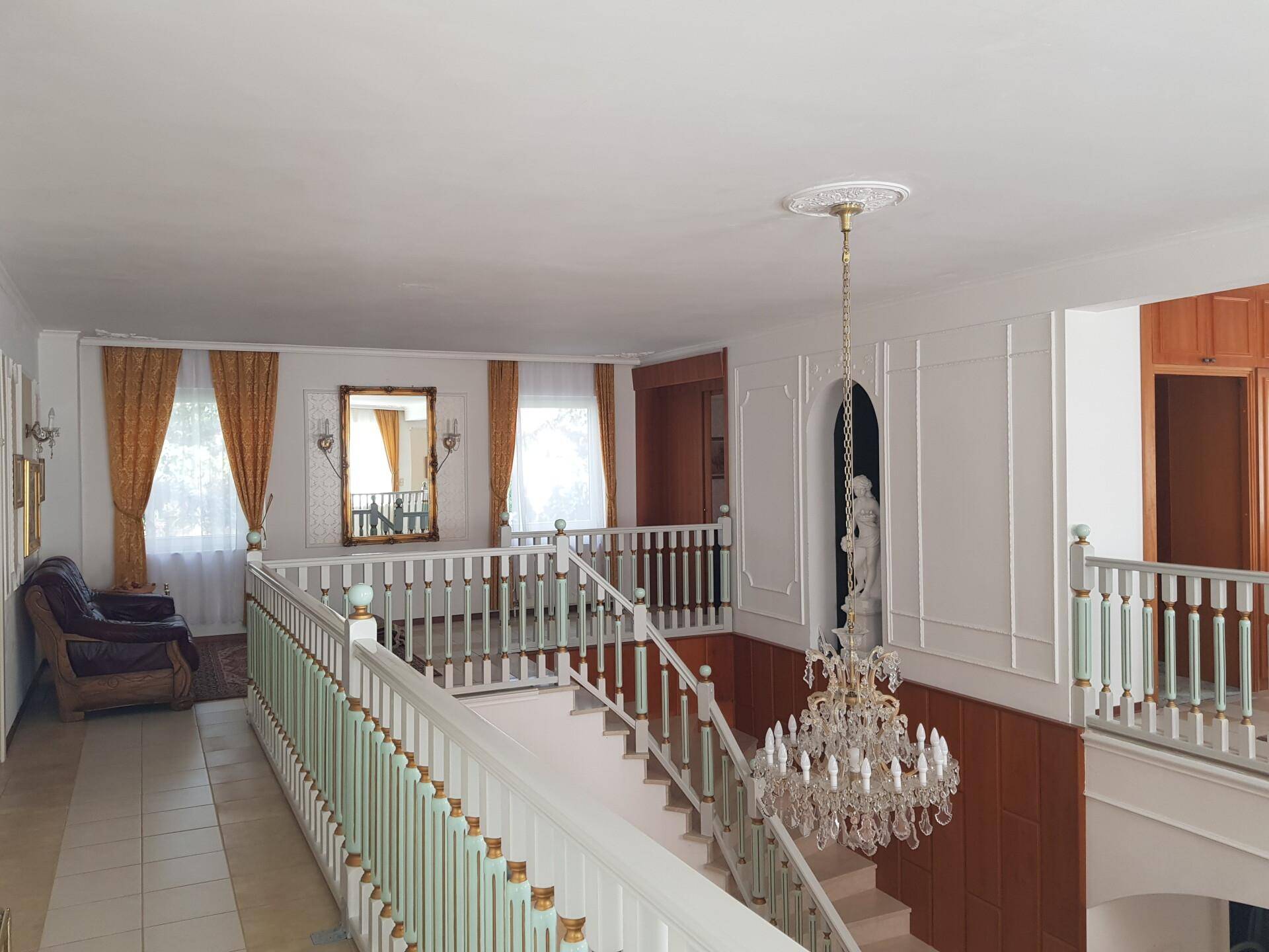 Obere Galerie mit Blick auf die Treppe und den Wohnbereich, ausgestattet mit klassischem Mobiliar.