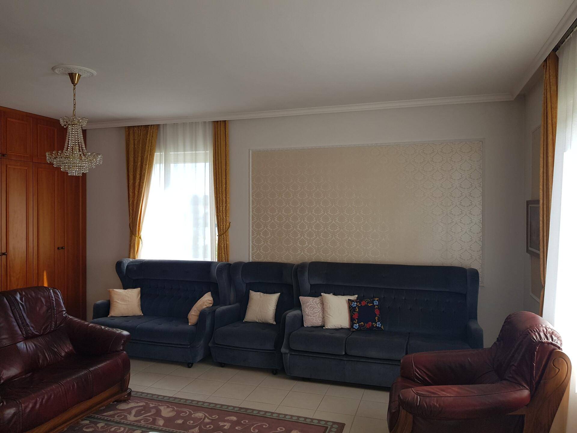 Gemütliches Wohnzimmer mit Teppichboden, bequemen Sofas und einem eleganten Kronleuchter.