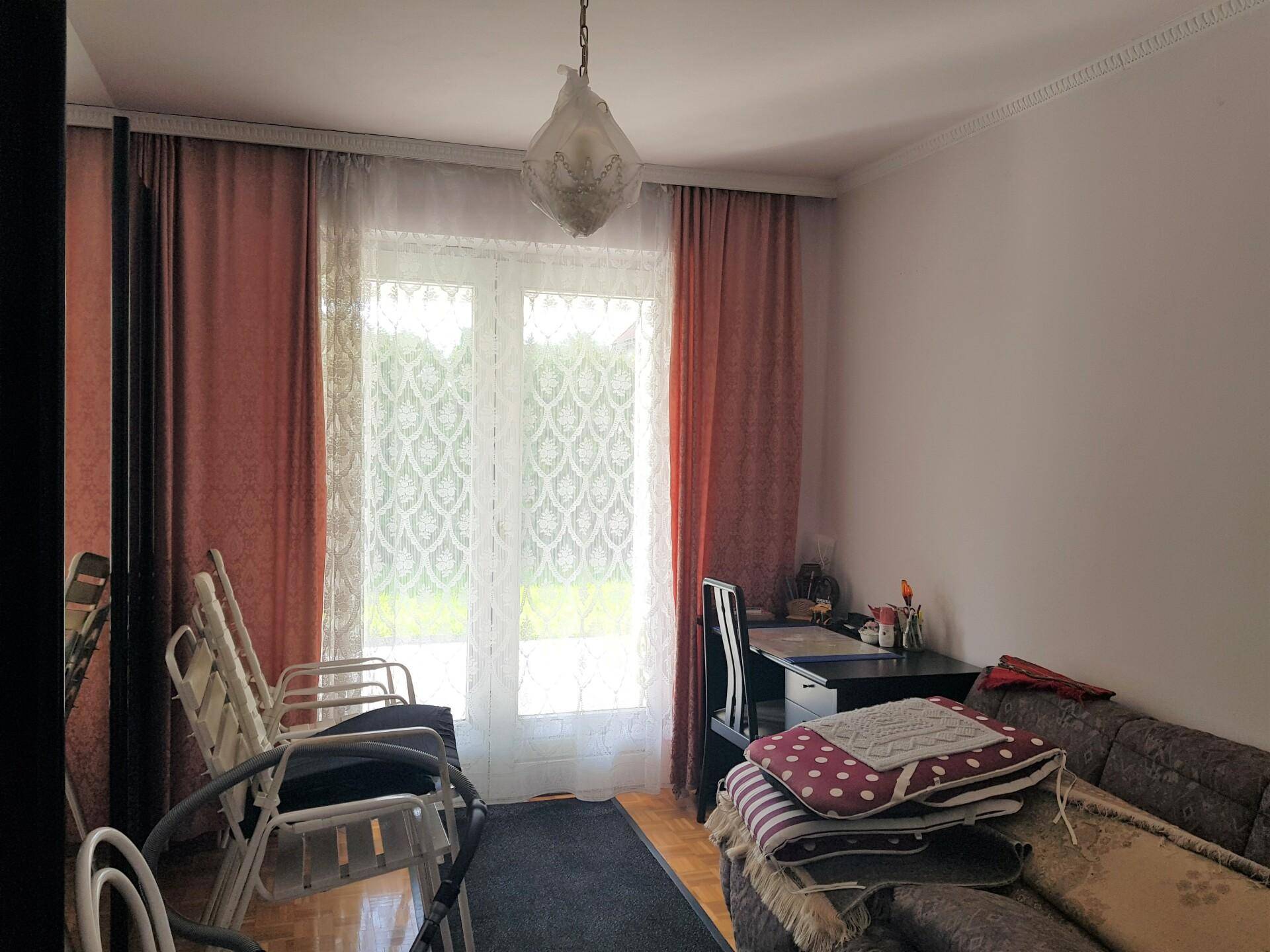 Helles Zimmer mit Parkettboden, Schreibtisch und Zugang zu einem Balkon oder einer Terrasse.