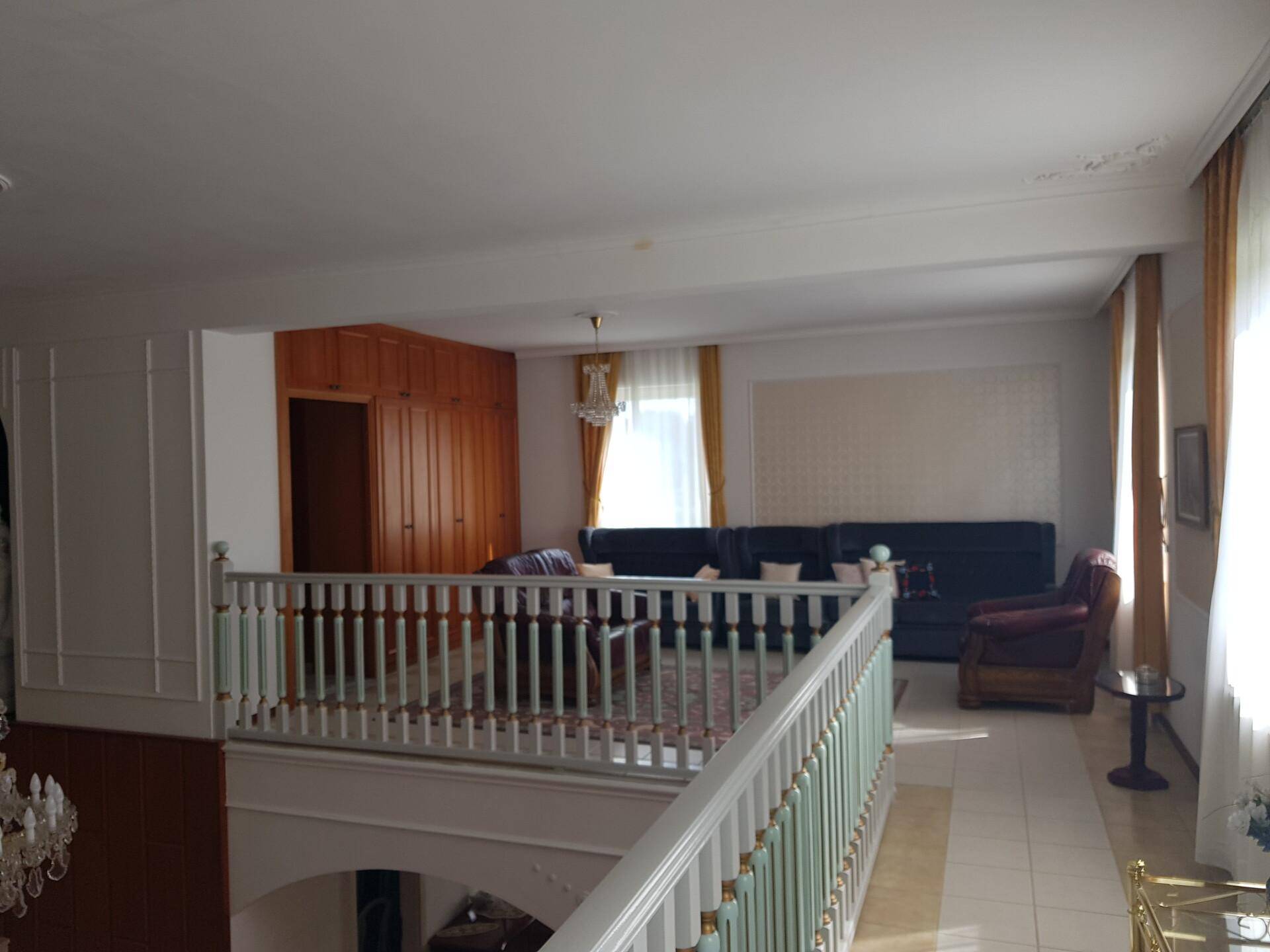 Geräumiges Wohnzimmer im Obergeschoss mit bequemen Sofas, Einbauschränken und großen Fenstern.