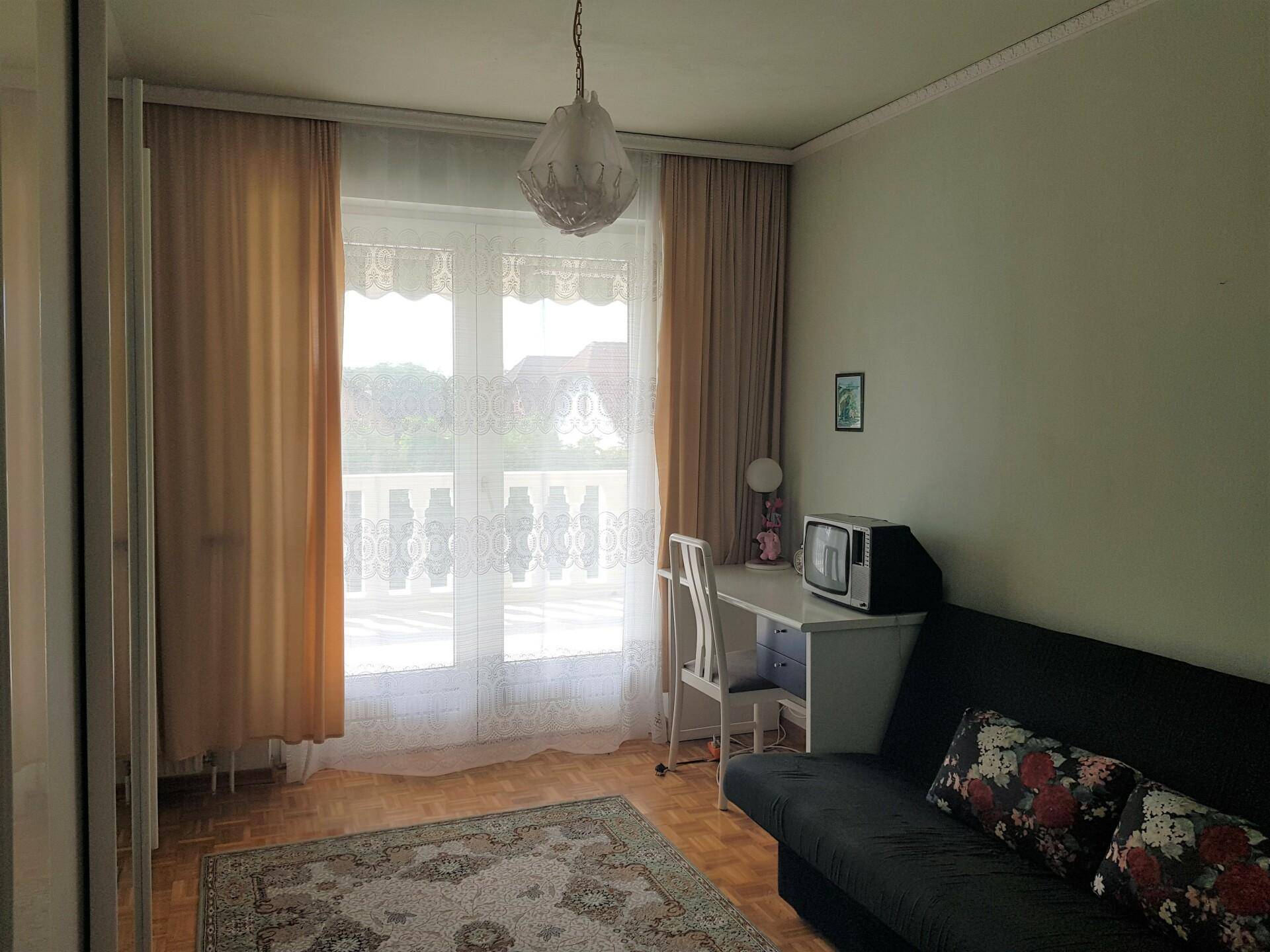 Gemütliches Schlafzimmer mit Doppelbett, Parkettboden und braunen Vorhängen, hell und einladend.