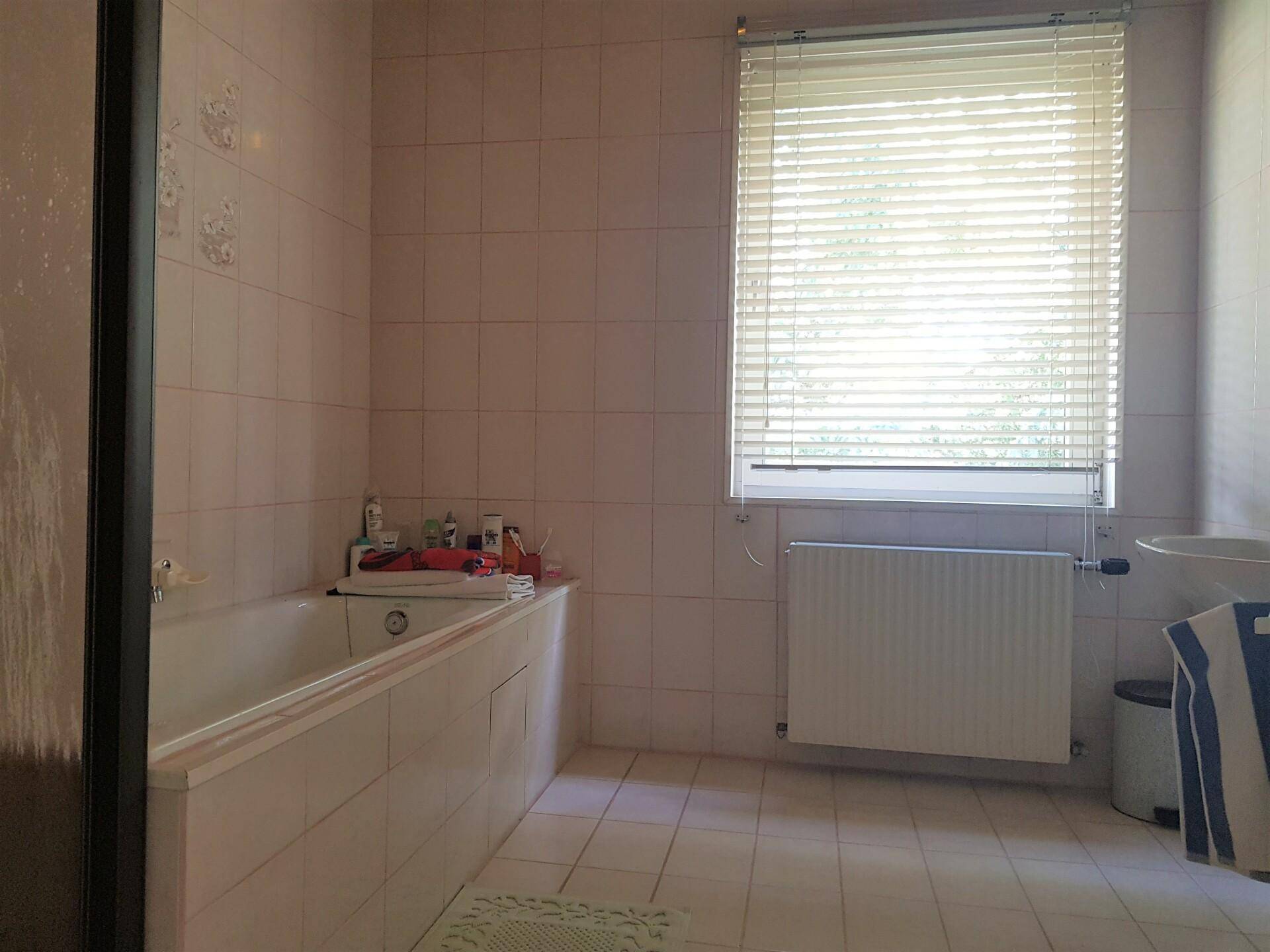 Separate Toilette mit Bidet und Fenster, komplett gefliest in hellem Farbton.
