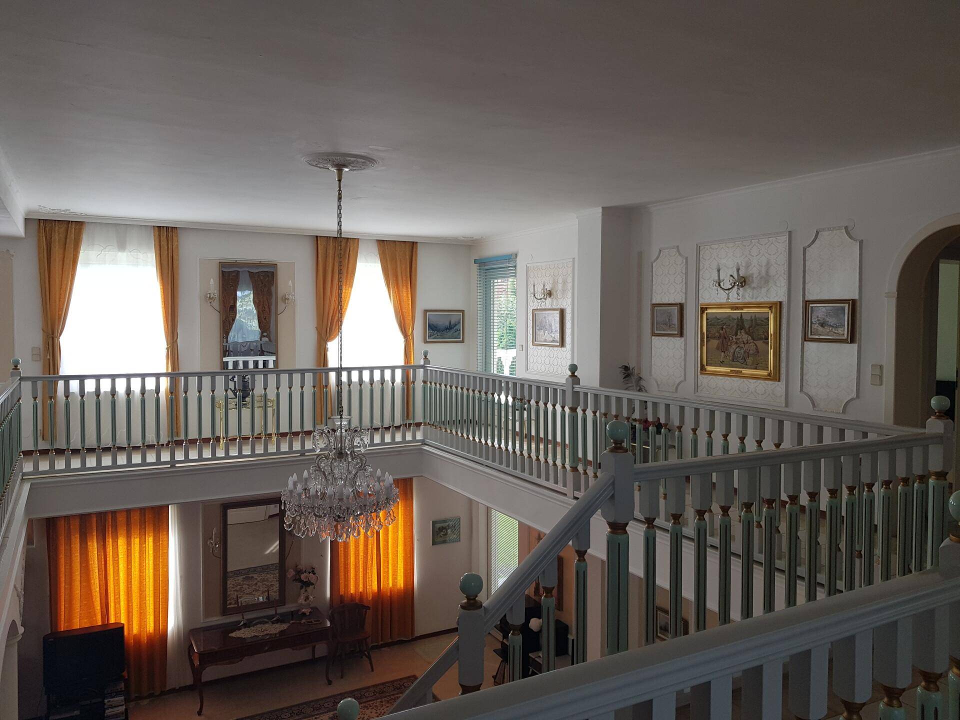 Helles Zimmer mit Parkettboden, Schreibtisch und Zugang zu einem Balkon oder einer Terrasse.
