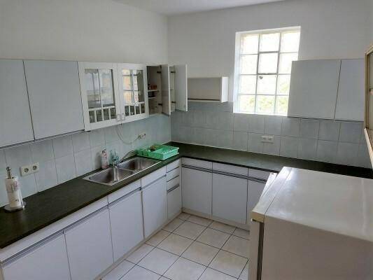 Funktionale Küche mit weißen Schränken, dunklen Arbeitsplatten und gefliestem Boden.