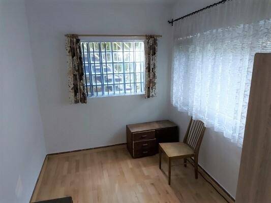 Kleines Zimmer mit Fenster, Kommode und Laminatboden, ideal als Gästezimmer.