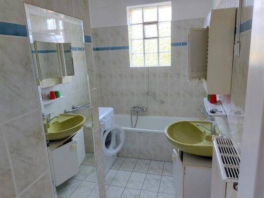 Badezimmer mit Badewanne, zwei grünen Waschbecken und Waschmaschine.