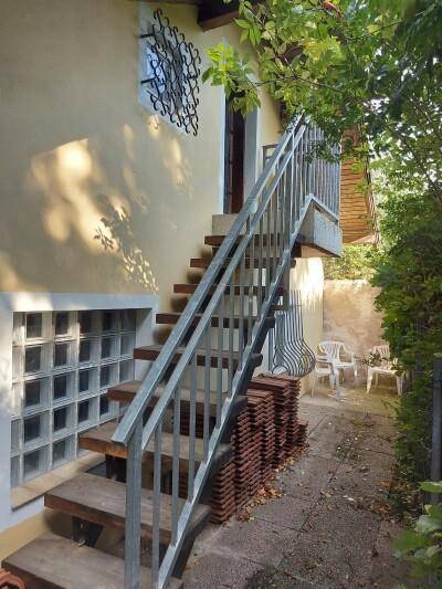 Außentreppe mit Metallgeländer führt zum oberen Eingang des Hauses.